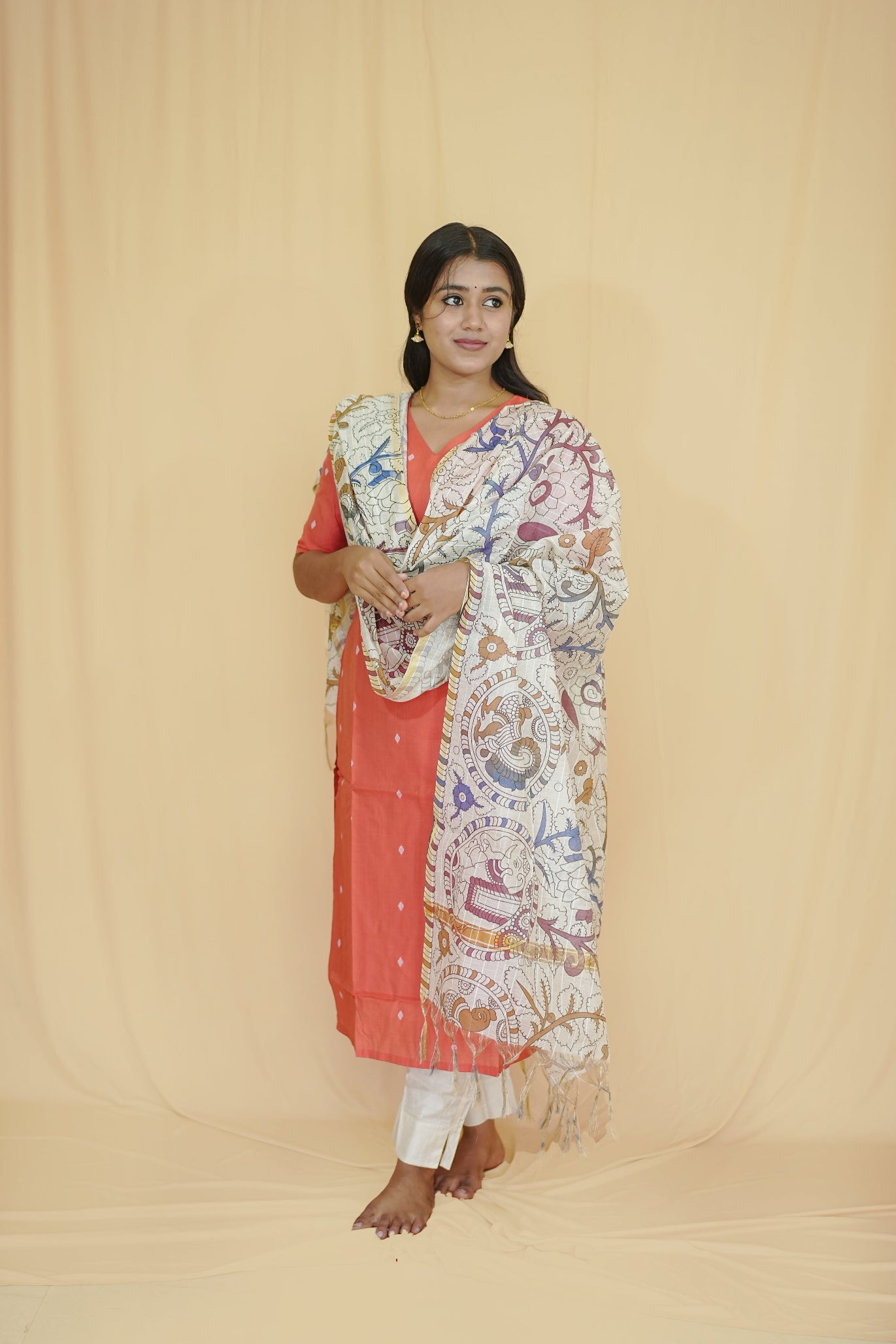 Woman wearing a traditional outfit with a patterned shawl on a beige background